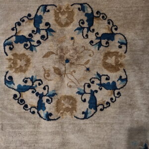 Muted beige rug with a detailed round medallion pattern featuring blue, light blue, and brown scrolling vines.
