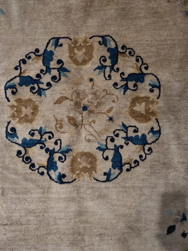 Muted beige rug with a detailed round medallion pattern featuring blue, light blue, and brown scrolling vines.