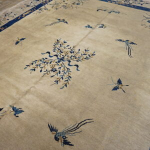 Tan rug with blue border, scattered bird pattern, and central floral bouquet on wood planks.
