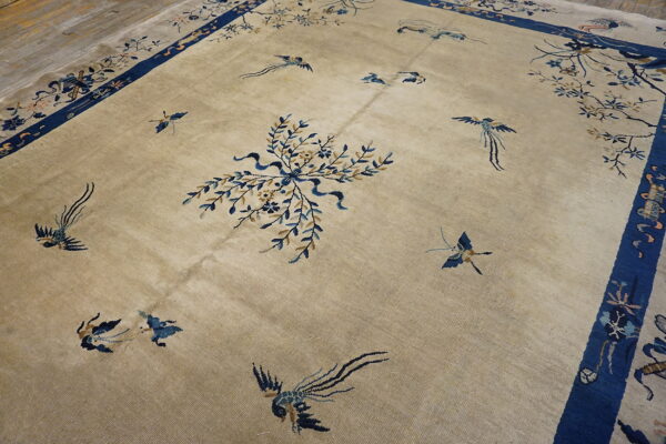 Tan rug with blue border, scattered bird pattern, and central floral bouquet on wood planks.