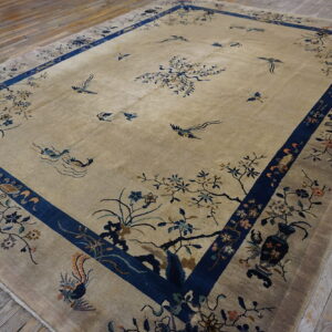Large beige rug with an indigo blue border displaying a detailed scenic bird and flower pattern on wood flooring.