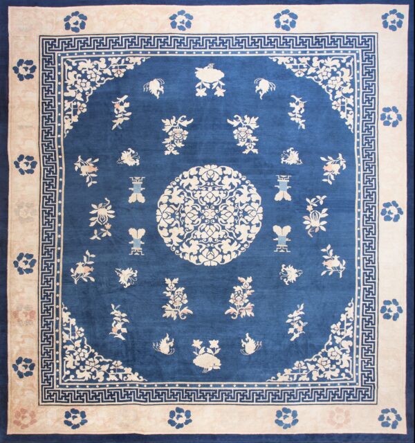 Blue and cream rug featuring a central floral medallion, scattered motifs, and geometric borders.