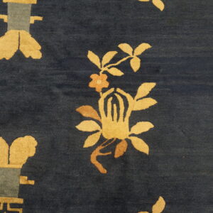 Dark blue rug close-up showing high pile and stylized golden yellow floral and geometric patterns.