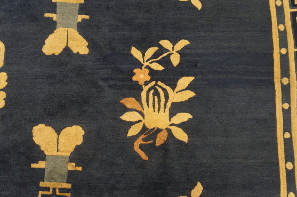 Dark blue rug close-up showing high pile and stylized golden yellow floral and geometric patterns.