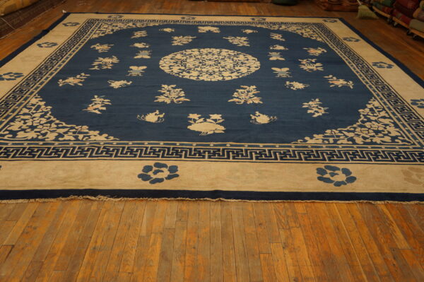Low-pile rug in blue and cream with a detailed floral and geometric meander pattern on wood planks.