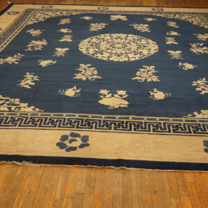 Large blue rug featuring scattered cream floral motifs, a central medallion, and a geometric border on wood floors.