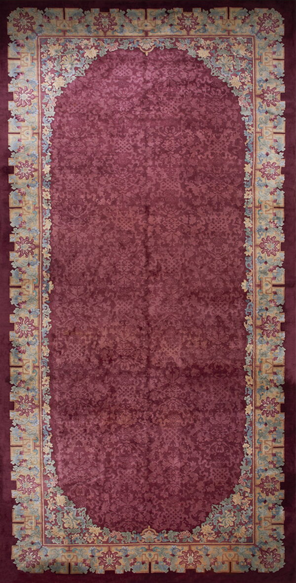 Burgundy rug with an ornate tone-on-tone field and broad, colorful floral and geometric borders.
