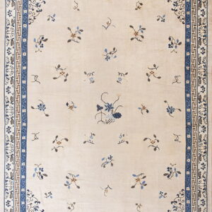 Light beige rug featuring scattered blue floral sprigs and an elaborate dark blue geometric border.