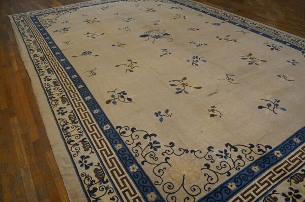 The beige rug has scattered blue and brown botanical motifs and an ornate blue border on wood planks.