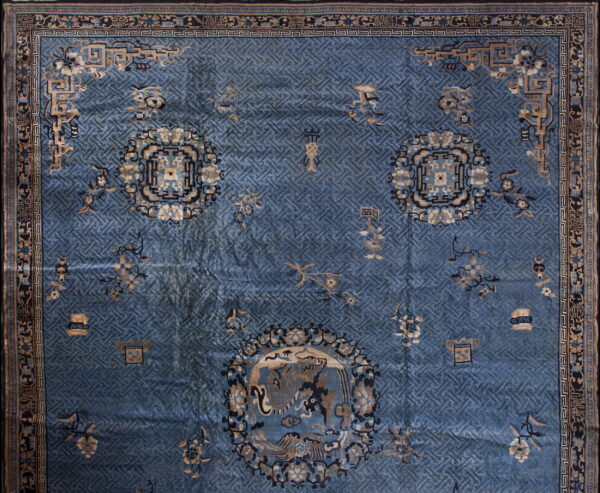 Blue low-pile rug featuring a complex lattice pattern, tan medallions, and thick geometric borders.