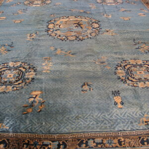 A pale blue rug with tan and navy traditional medallions and a subtle trellis pattern lies on wood floor.