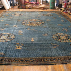 Large, low-pile rug with a blue lattice field and tan medallions on hardwood plank flooring.