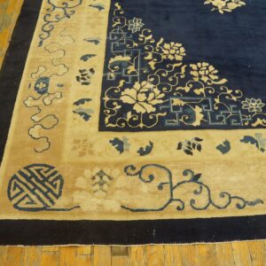 Navy blue field and tan border rug featuring intricate traditional motifs rests on distressed wood planks.