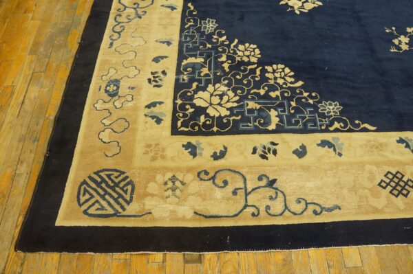 Navy blue field and tan border rug featuring intricate traditional motifs rests on distressed wood planks.