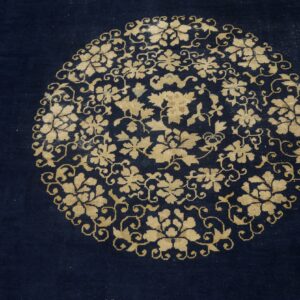 Dark blue rug detail showing a dense circular gold floral and scrolling vine medallion.
