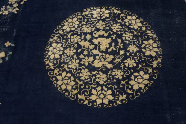 Dark blue rug detail showing a dense circular gold floral and scrolling vine medallion.