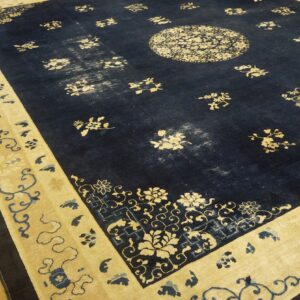 Navy blue rug with a cream floral medallion and wide border displayed on a plank wood floor.