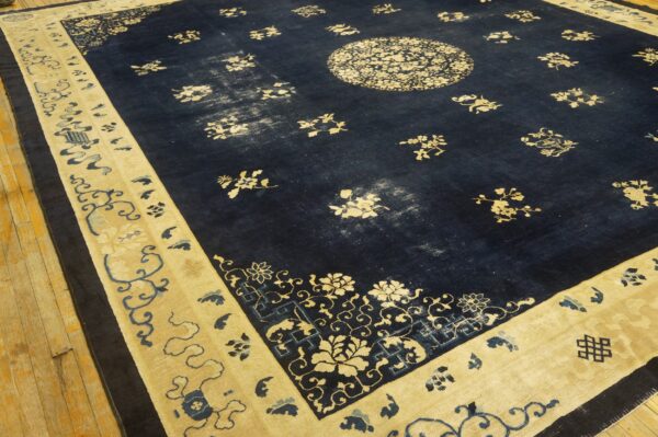 Navy blue rug with a cream floral medallion and wide border displayed on a plank wood floor.