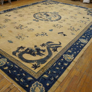 Cream rug with indigo blue dragon and cloud patterns, surrounded by a wide border on wood floors.