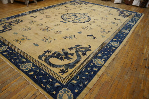Cream rug with indigo blue dragon and cloud patterns, surrounded by a wide border on wood floors.