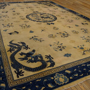 Beige rug featuring navy blue dragon, cloud, and floral patterns with geometric borders on wood.