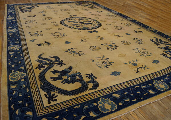 Beige rug featuring navy blue dragon, cloud, and floral patterns with geometric borders on wood.