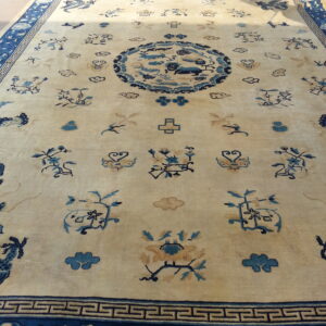 Beige rug with dark blue dragon, cloud, and floral motifs surrounding a large central design.