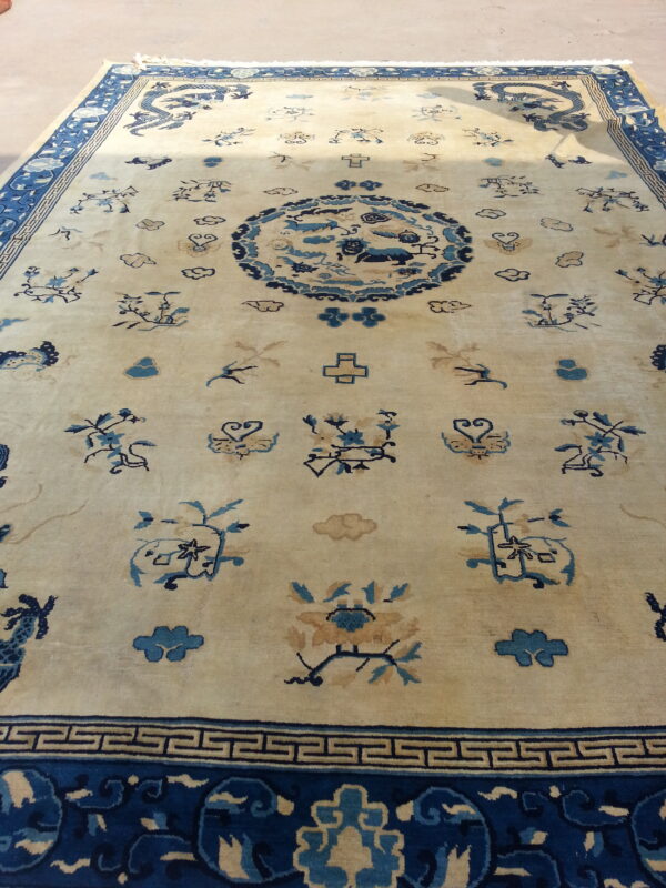 Beige rug with dark blue dragon, cloud, and floral motifs surrounding a large central design.