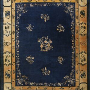 Rectangular rug with a dark blue field and contrasting golden tan border featuring floral and decorative panels.