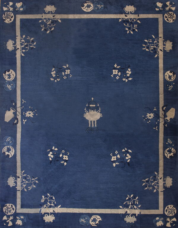 Deep indigo rug with a beige framed border and scattered stylized floral and vessel motifs.