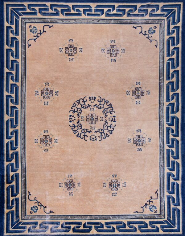 Tan and blue rug featuring a bold greek key border and geometric central motifs on plank wood floor.