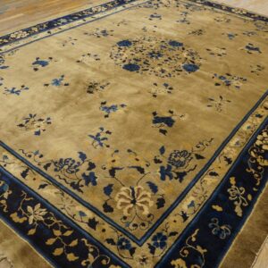 Gold-toned rug featuring a central medallion and scattered blue floral sprays on distressed hardwood flooring.