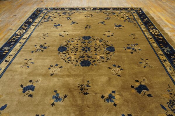 Olive rug with a central blue floral medallion and navy border rests on worn wooden planks.