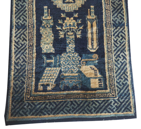 Thick navy blue rug with tan and teal stylized patterns and detailed geometric borders.
