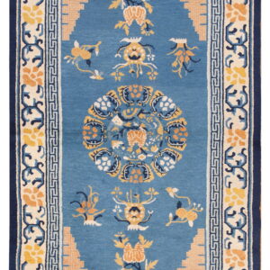 Blue rug with elaborate yellow and peach stylized patterns and multiple navy and ivory borders.