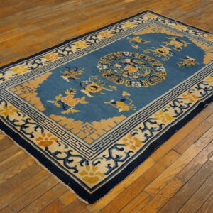 Teal and gold floral patterned rug with dark blue borders on distressed wood floors.