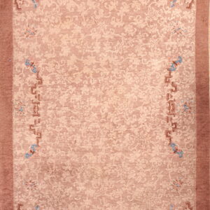Muted pink area rug featuring tone-on-tone botanical designs and geometric borders with blue accents.