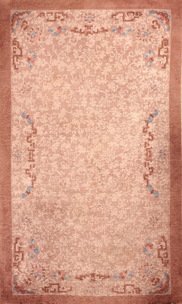 Muted pink area rug featuring tone-on-tone botanical designs and geometric borders with blue accents.