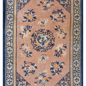 Dusty rose rug with navy and tan borders, featuring traditional floral sprays and a circular central motif.