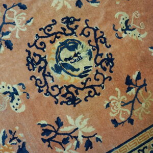 Muted terracotta rug featuring navy and gold stylized florals surrounding a central animal medallion.