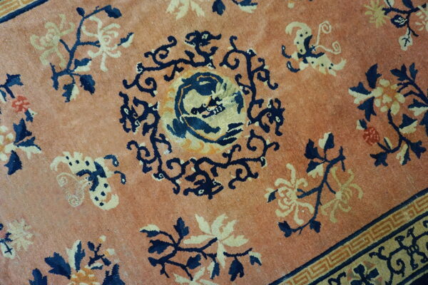 Muted terracotta rug featuring navy and gold stylized florals surrounding a central animal medallion.