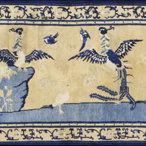 Beige and dark blue rug featuring stylized birds, rock formations, and ornate vine borders.
