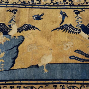 The rug has a tan field patterned with deep blue birds, rock formations, and elaborate blue borders.