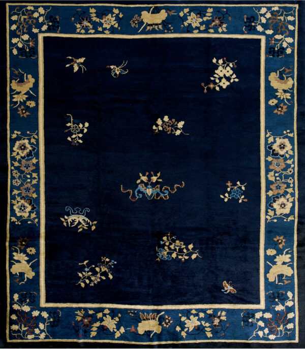 Plush navy rug with scattered floral and figural motifs, bordered in beige and blue on wood flooring.