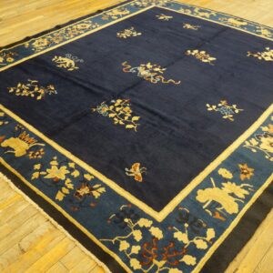 Dark blue rug featuring gold floral and stylized animal patterns within wide blue-tone borders on wood flooring.