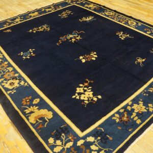 Dark blue area rug with gold and russet floral patterns and a wide teal and ochre decorative border.