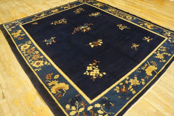 Dark blue area rug with gold and russet floral patterns and a wide teal and ochre decorative border.