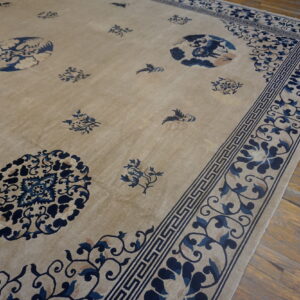 Beige rug with traditional dark blue floral and Greek key borders rests on distressed wood planks.