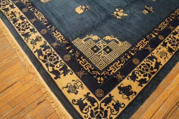 Low-pile rug in deep blue and gold with elaborate borders and fringe rests on rustic wood planks.