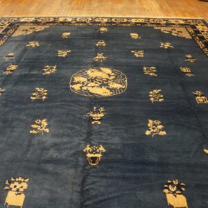 Deep blue rug with gold traditional patterns, central medallion, and wide borders on hardwood flooring.